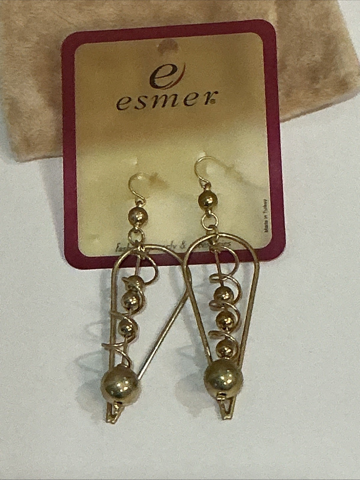Esmer brand gold-tone dangle earrings feature a distinctive geometric triangle