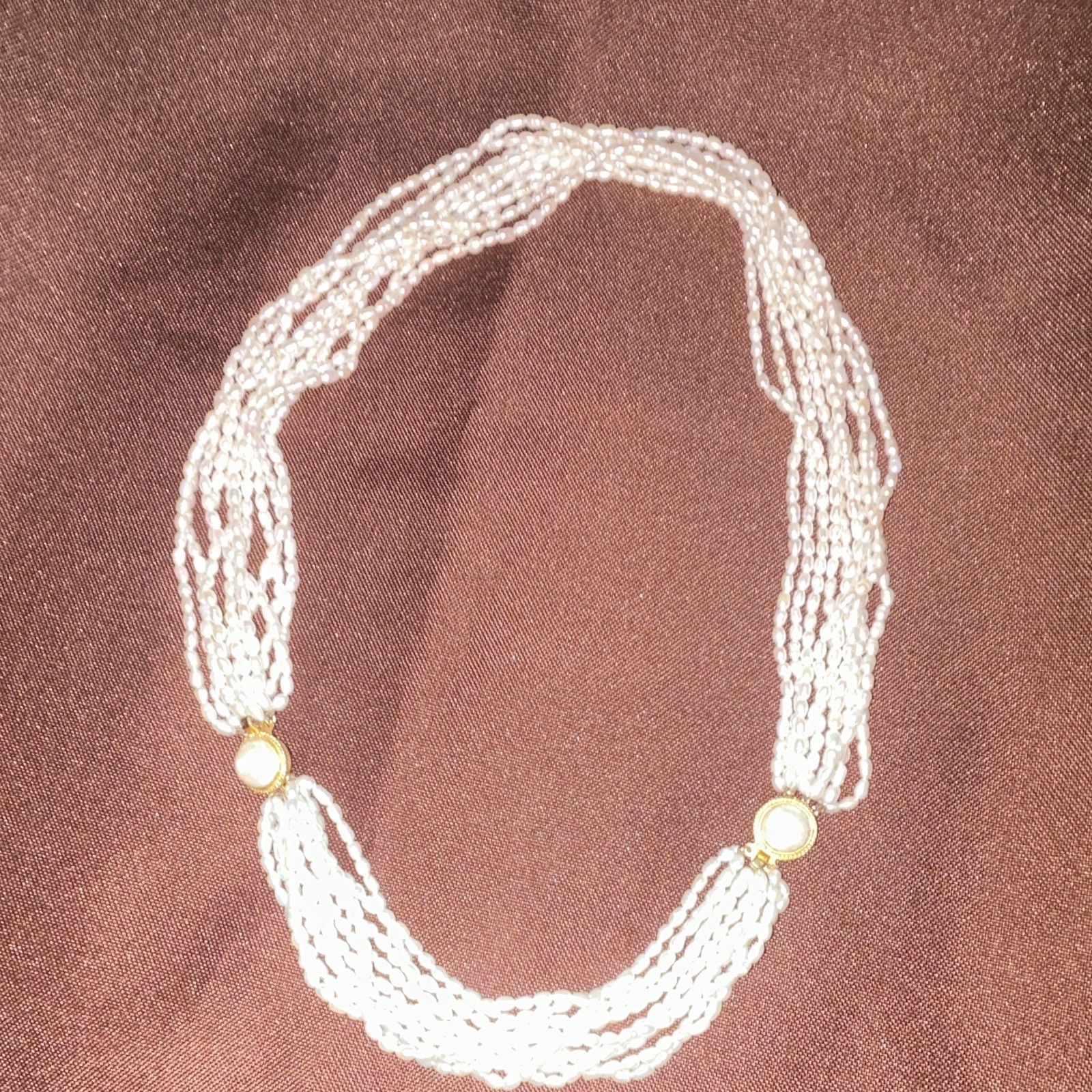 This multi-strand freshwater rice pearl necklace features distinctive gold-tone