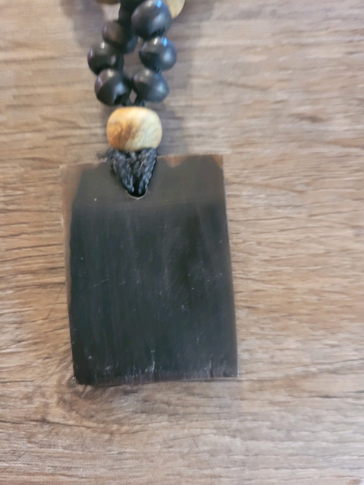 handmade artisan necklace pendant with a textured wood grain finish on a Cord