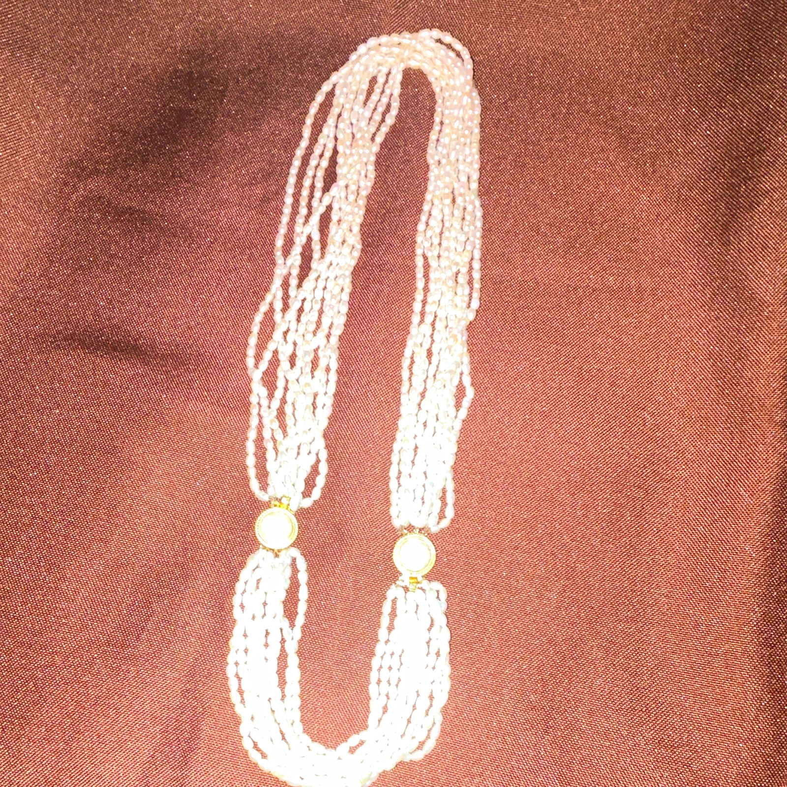 This multi-strand freshwater rice pearl necklace features distinctive gold-tone
