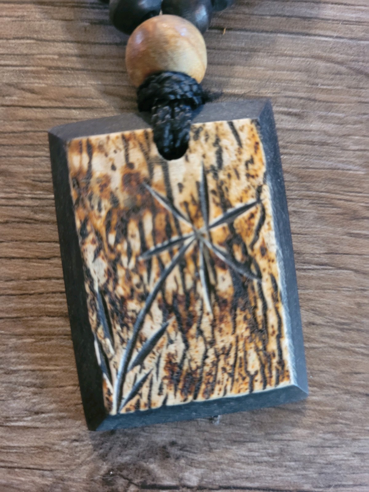 handmade artisan necklace pendant with a textured wood grain finish on a Cord