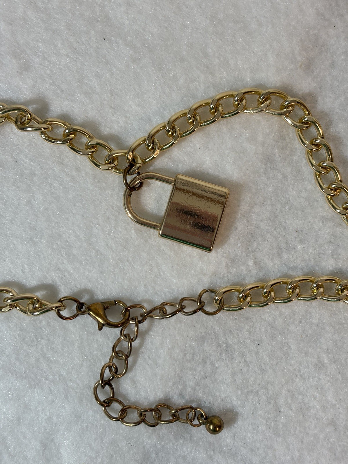 Gold-tone curb-link chain necklace with a small padlock pendant.