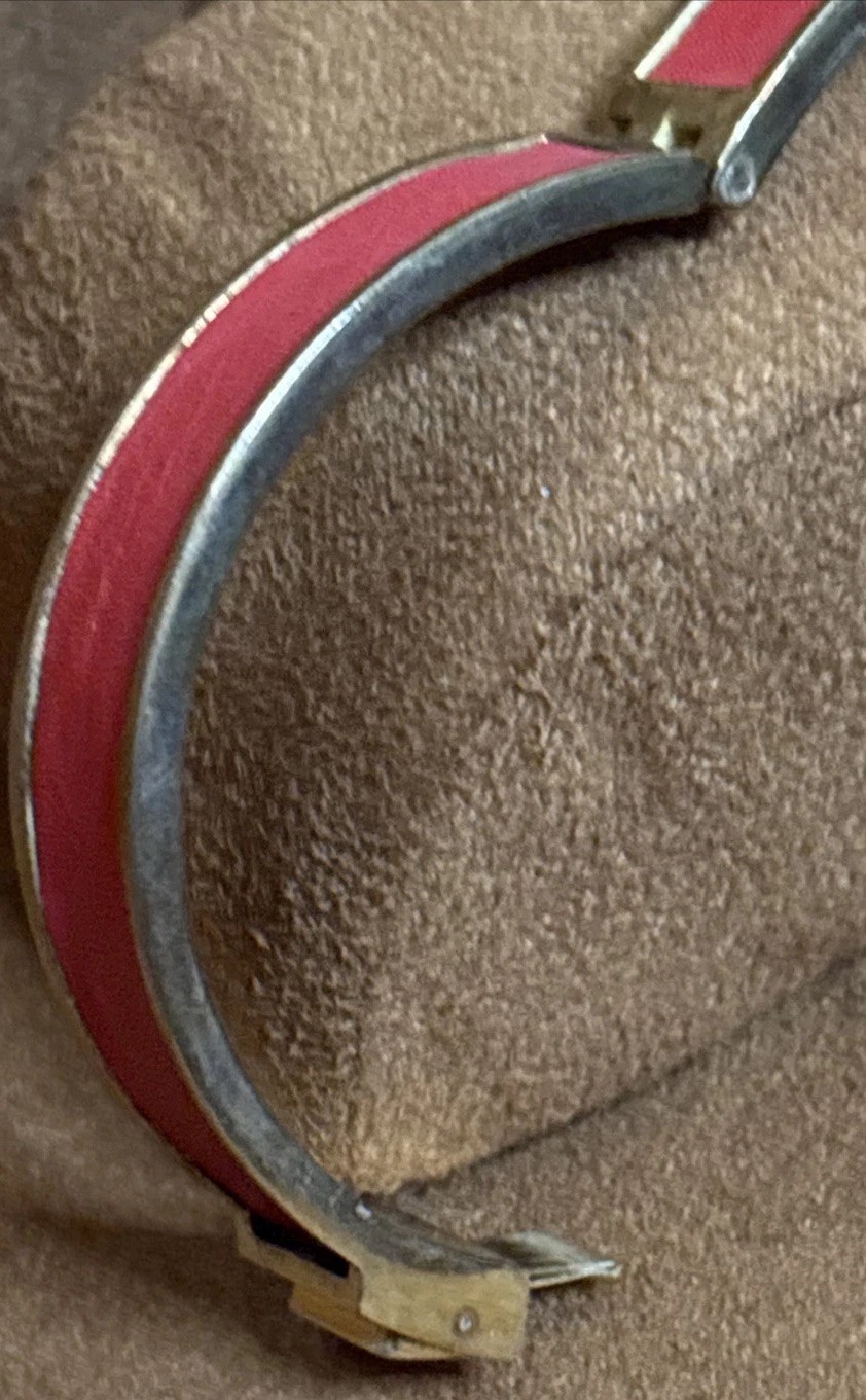 Henri Bendel red leather bangle features a gold-tone metal bar set rhinestones.