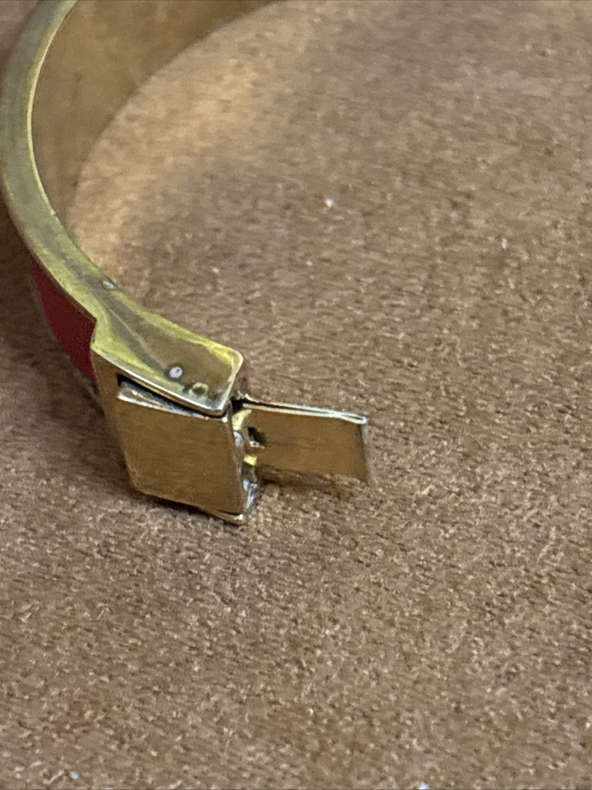 Henri Bendel red leather bangle features a gold-tone metal bar set rhinestones.