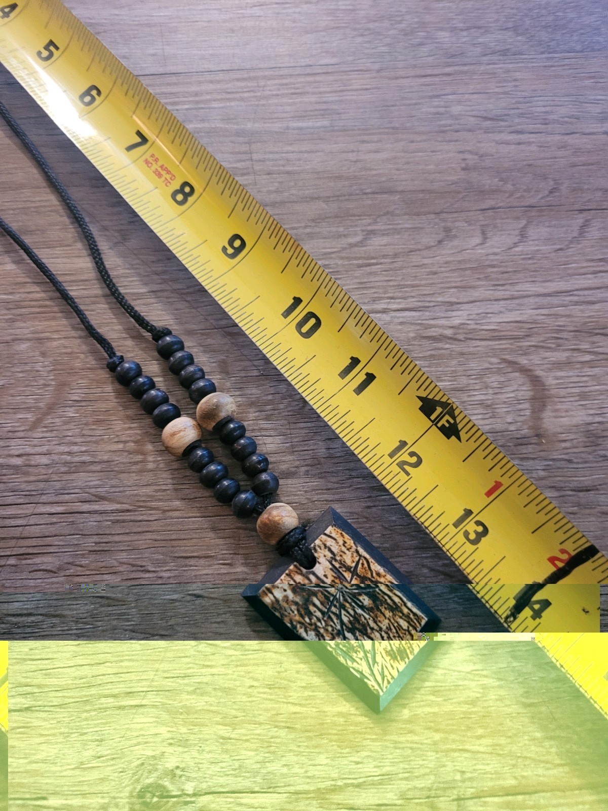 handmade artisan necklace pendant with a textured wood grain finish on a Cord