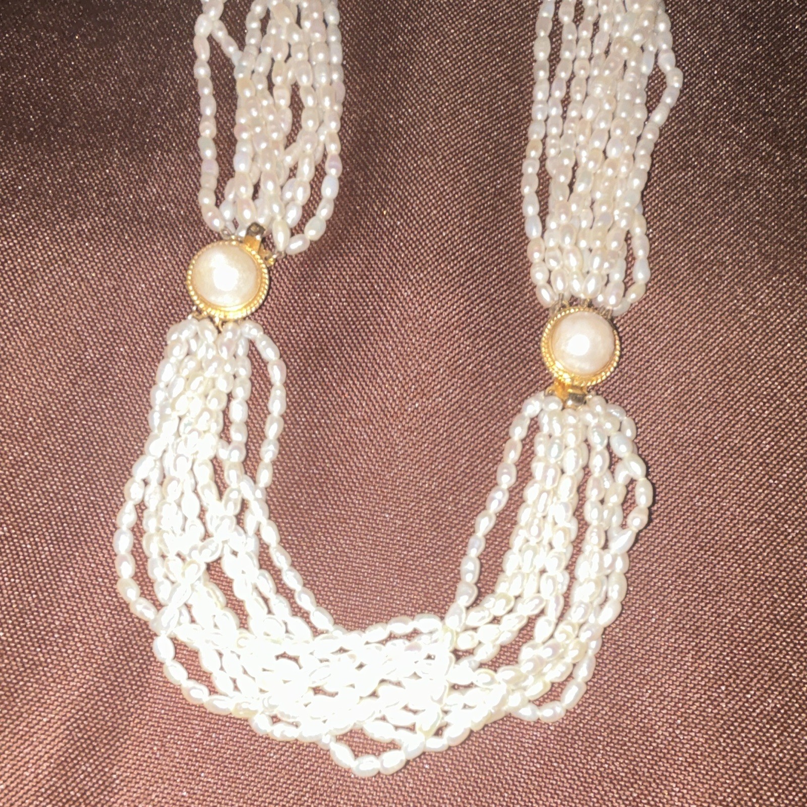 This multi-strand freshwater rice pearl necklace features distinctive gold-tone