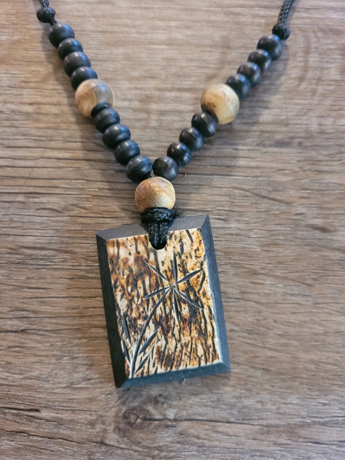 handmade artisan necklace pendant with a textured wood grain finish on a Cord