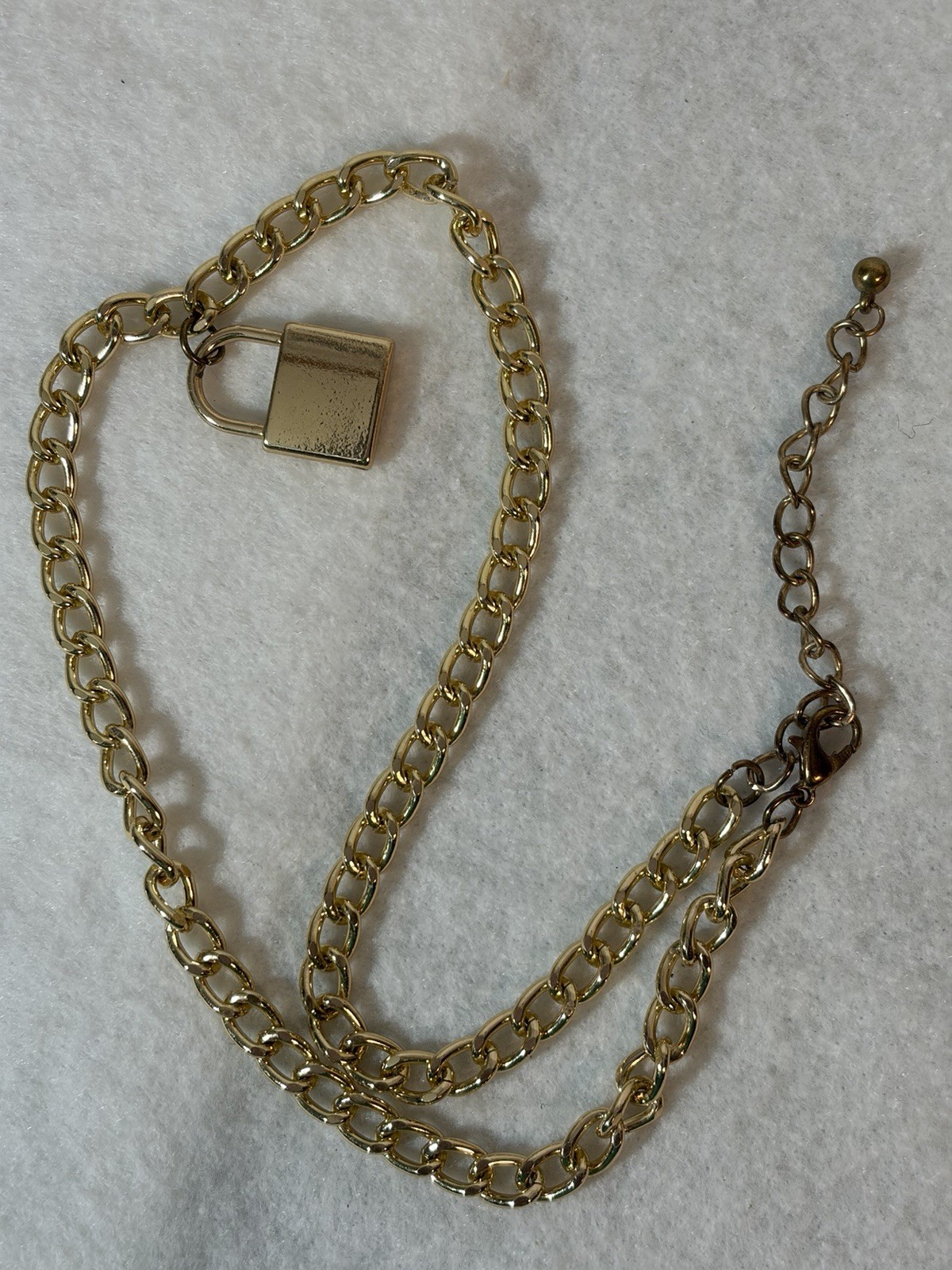 Gold-tone curb-link chain necklace with a small padlock pendant.