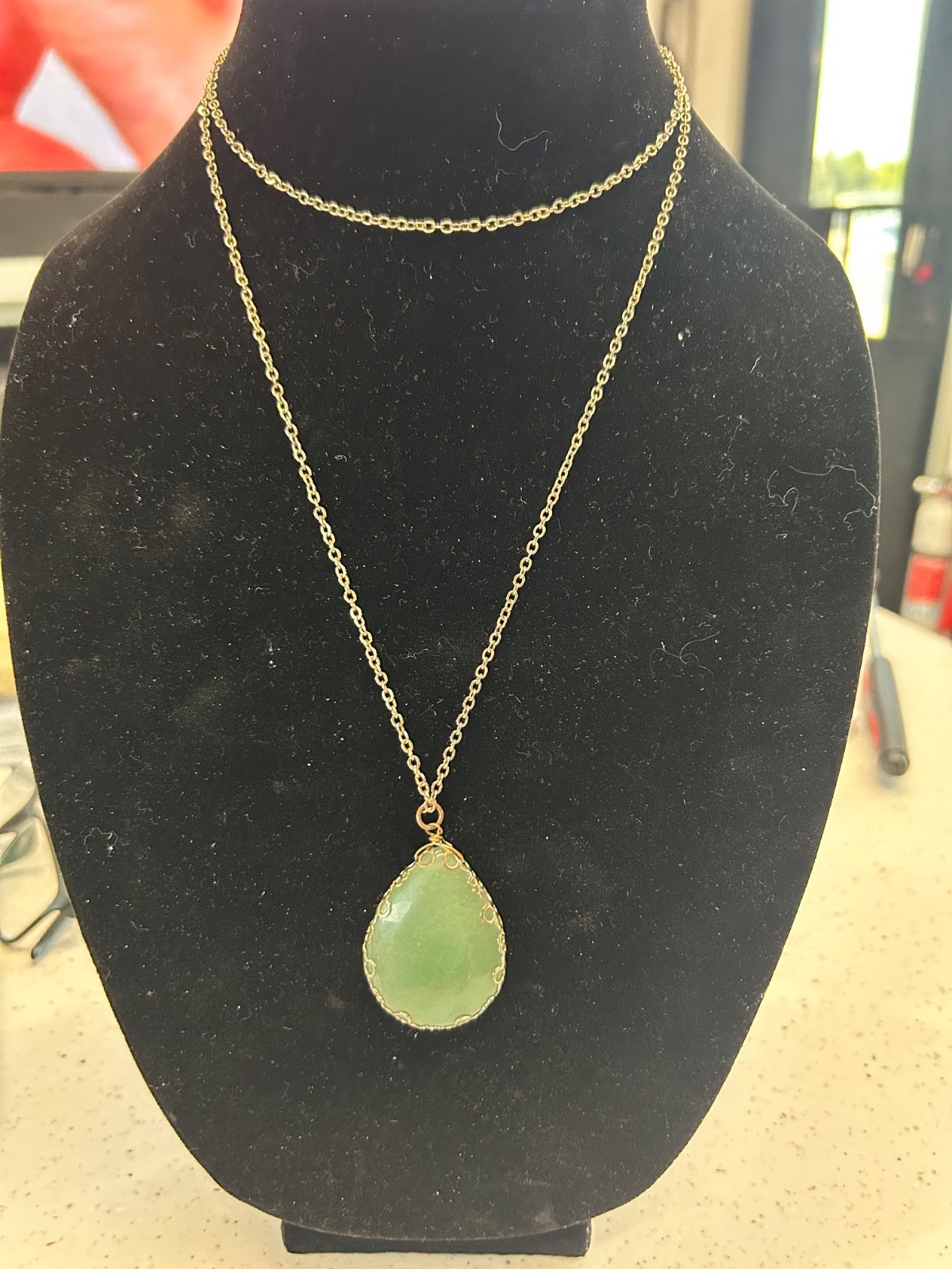 Gold toned necklace with large green stone pendant