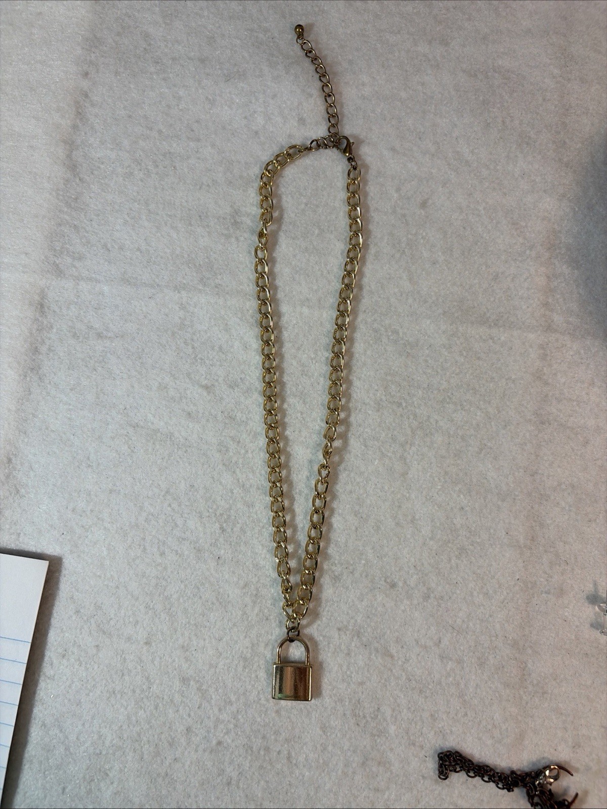 Gold-tone curb-link chain necklace with a small padlock pendant.